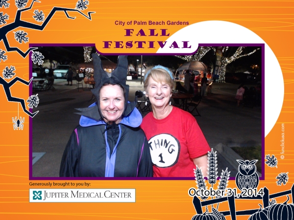 A woman dressed as Maleficent  and a woman dressed as Thing 1 smile for camera. Photo has orange border with tree branch, moon, fence, owl and pumpkins. Text 